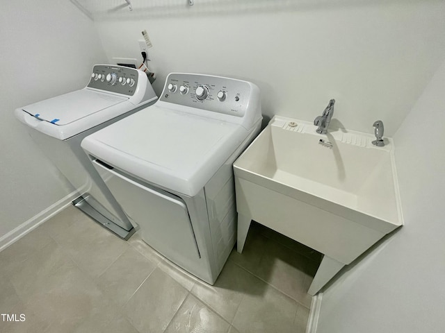 laundry room featuring light tile patterned floors, sink, and separate washer and dryer