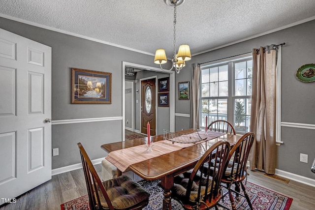 dining room with a textured ceiling, dark hardwood / wood-style flooring, crown molding, and a chandelier