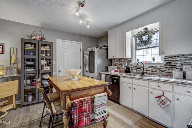 kitchen with sink, white cabinetry, dishwasher, and stainless steel fridge