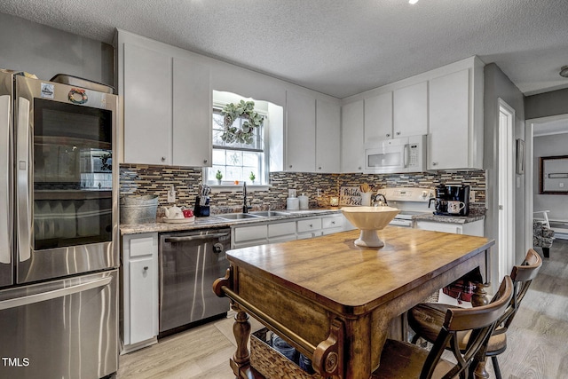 kitchen featuring sink, white cabinetry, a textured ceiling, and appliances with stainless steel finishes