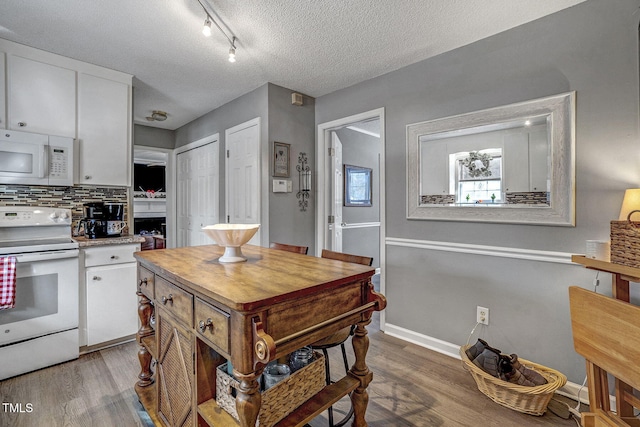 kitchen with backsplash, white cabinets, hardwood / wood-style floors, white appliances, and a textured ceiling