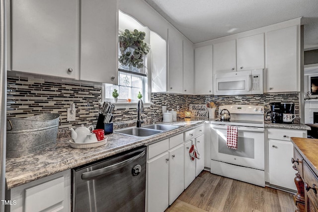 kitchen with white cabinets, light wood-type flooring, white appliances, and sink