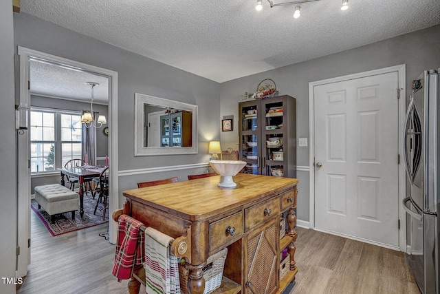 dining space with light hardwood / wood-style floors, a textured ceiling, and an inviting chandelier