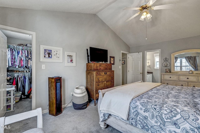 bedroom with ceiling fan, ensuite bath, a walk in closet, a closet, and lofted ceiling