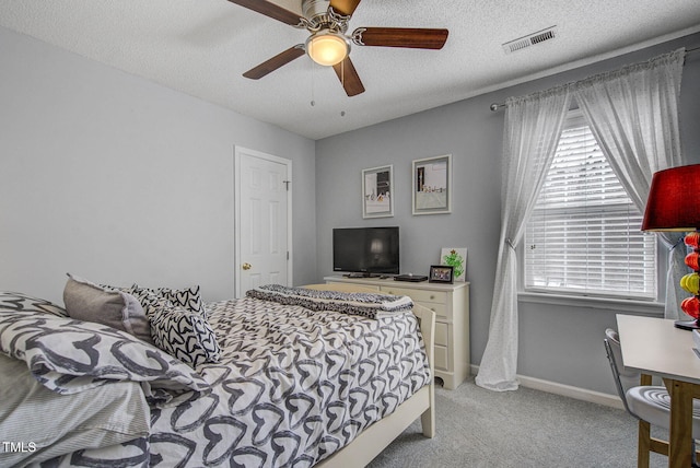 bedroom featuring ceiling fan, light colored carpet, and a textured ceiling