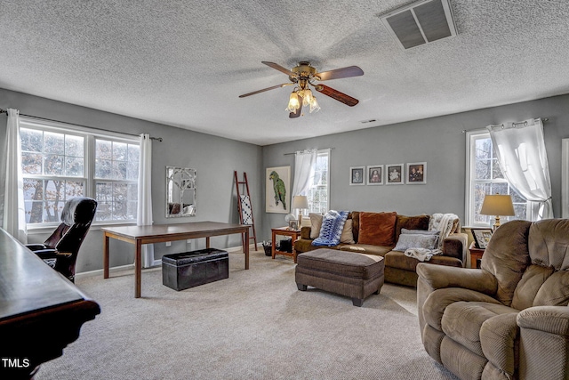 living room featuring ceiling fan, a wealth of natural light, light colored carpet, and a textured ceiling