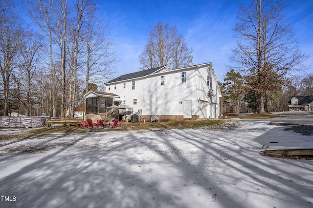 snow covered property with a garage and a sunroom