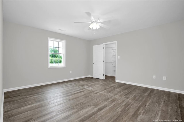 unfurnished bedroom featuring ceiling fan, a spacious closet, a closet, and dark hardwood / wood-style floors