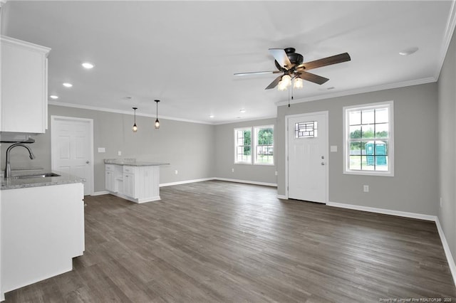 unfurnished living room featuring dark wood-type flooring, sink, crown molding, and ceiling fan