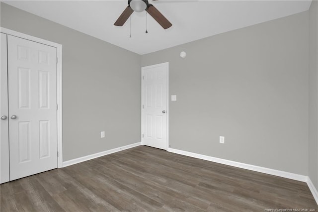 unfurnished bedroom featuring dark wood-type flooring, ceiling fan, and a closet