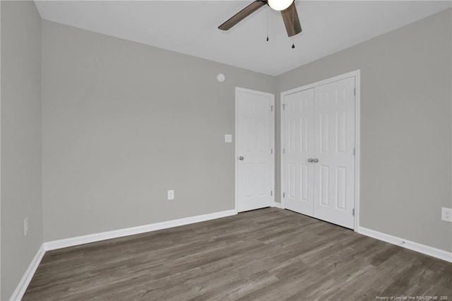 unfurnished bedroom with ceiling fan, dark hardwood / wood-style flooring, and a closet