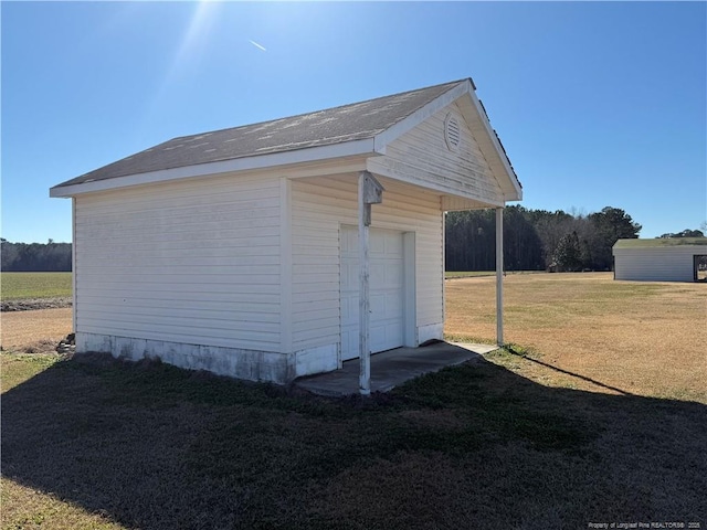 view of side of property with a garage, a lawn, and an outdoor structure