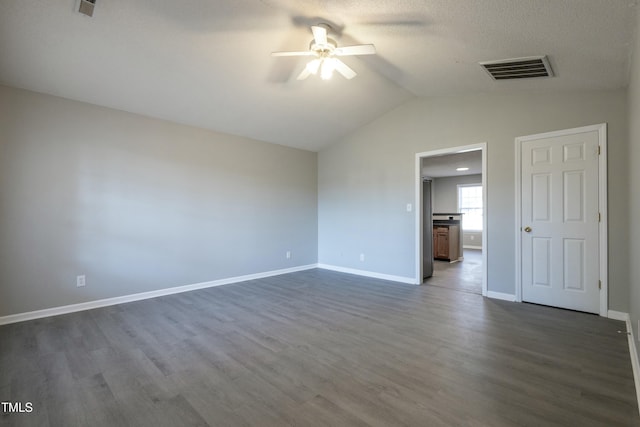 empty room featuring ceiling fan, vaulted ceiling, dark hardwood / wood-style floors, and a textured ceiling