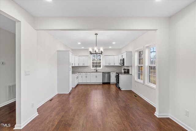 kitchen with white cabinetry, tasteful backsplash, decorative light fixtures, appliances with stainless steel finishes, and a notable chandelier