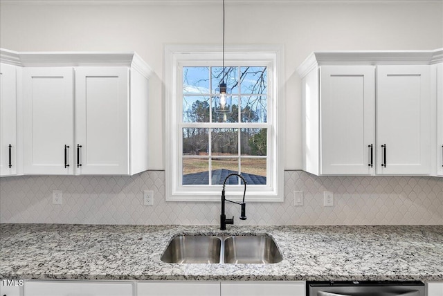 kitchen with dishwasher, sink, white cabinets, hanging light fixtures, and light stone countertops