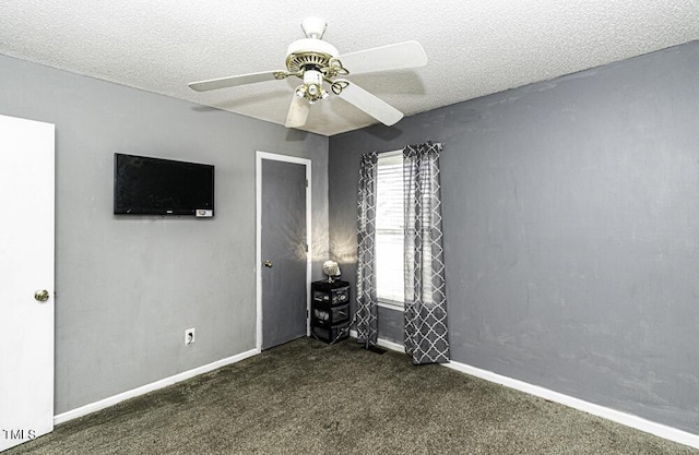 unfurnished bedroom with ceiling fan, dark carpet, and a textured ceiling