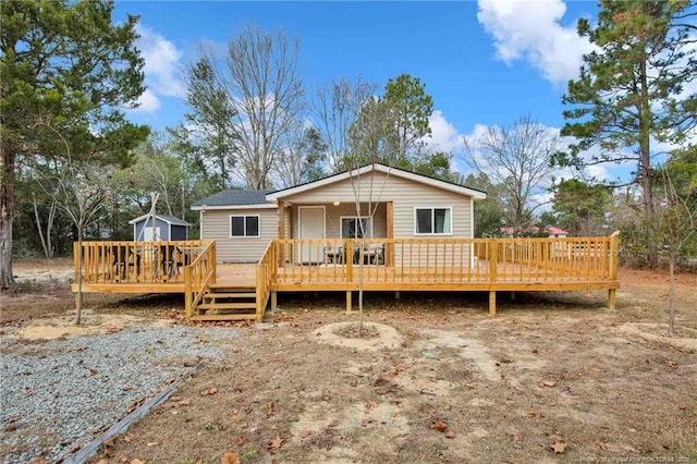 back of house with a storage shed and a deck