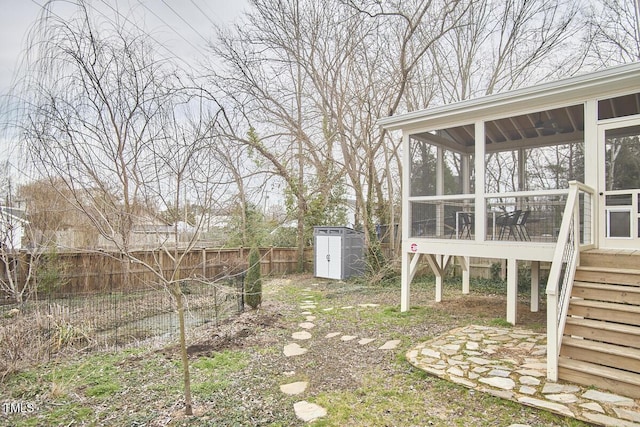 view of yard with a fenced backyard, an outdoor structure, a sunroom, stairway, and a storage unit