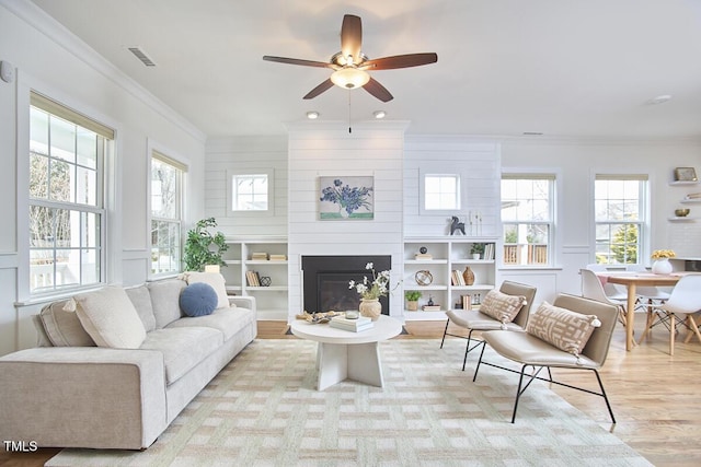 interior space featuring light wood-style floors, a fireplace, visible vents, and ornamental molding