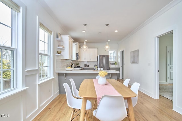 dining space with crown molding, light wood-type flooring, plenty of natural light, and baseboards