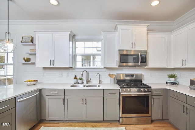 kitchen featuring open shelves, light countertops, gray cabinetry, appliances with stainless steel finishes, and a sink