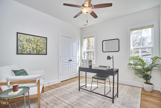 office featuring ceiling fan, visible vents, baseboards, and wood finished floors