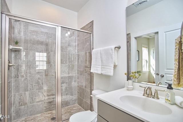 bathroom with toilet, a stall shower, visible vents, and vanity