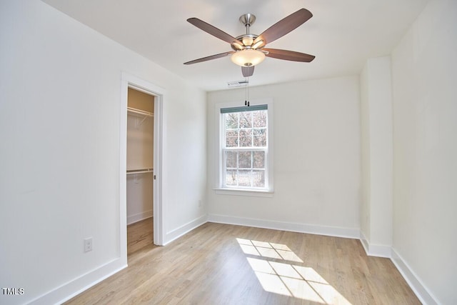 unfurnished bedroom featuring light wood-type flooring, visible vents, a spacious closet, and baseboards