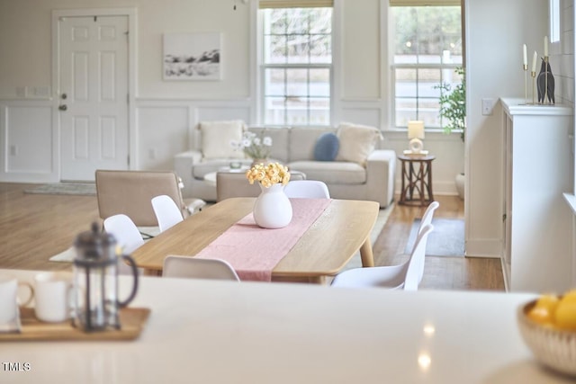 interior space featuring wainscoting, a decorative wall, and wood finished floors