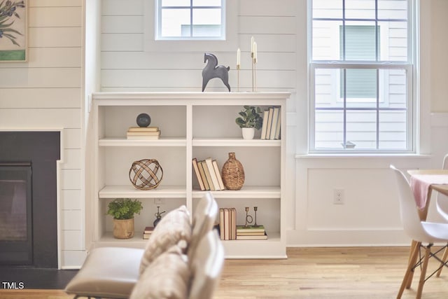 interior space with built in shelves, a fireplace, and wood finished floors