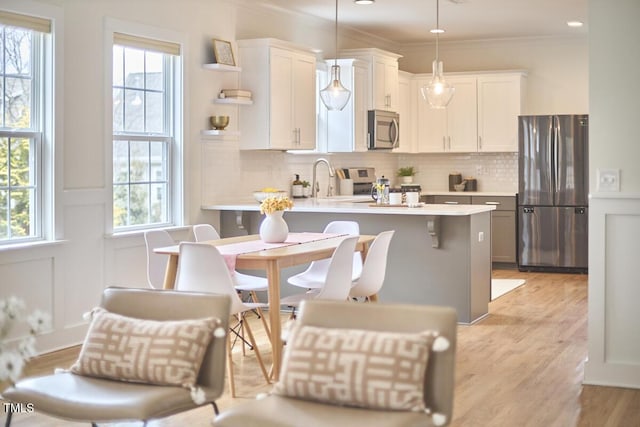 kitchen featuring a peninsula, a breakfast bar, light countertops, appliances with stainless steel finishes, and pendant lighting