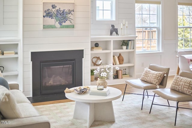 interior space with light wood-style flooring, built in shelves, and a fireplace with flush hearth