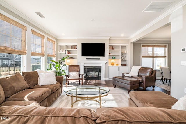 living room with built in features, ornamental molding, and light hardwood / wood-style floors