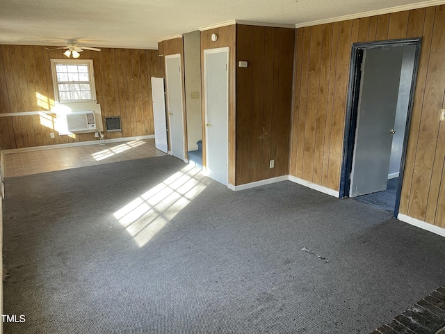 unfurnished living room featuring ceiling fan, ornamental molding, dark carpet, and wood walls