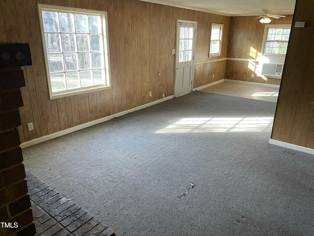 spare room featuring carpet, cooling unit, ceiling fan, and wood walls