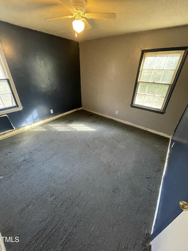 carpeted empty room with ceiling fan and a textured ceiling