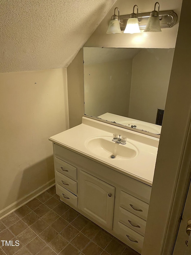 bathroom featuring vanity, vaulted ceiling, and a textured ceiling