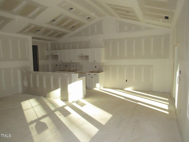 interior space featuring high vaulted ceiling and white cabinetry