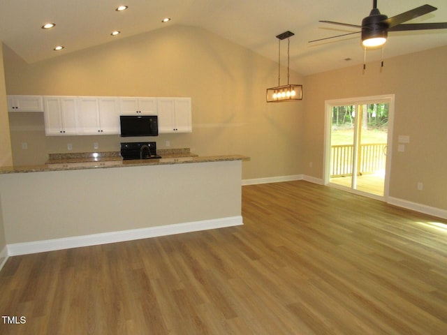 122 Beaver Trl, Littleton, NC 27850 - kitchen with black microwave, lofted ceiling, white cabinets, range, and recessed lighting