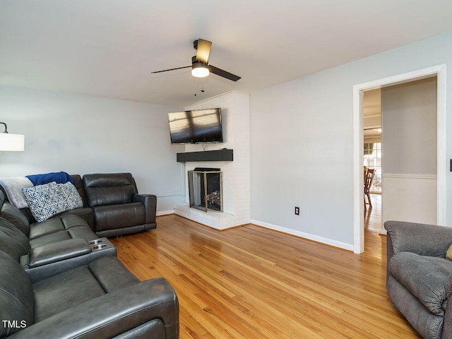 living room featuring ceiling fan, hardwood / wood-style floors, and a fireplace