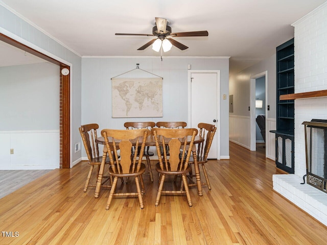 dining room featuring a fireplace, ornamental molding, light hardwood / wood-style floors, and ceiling fan