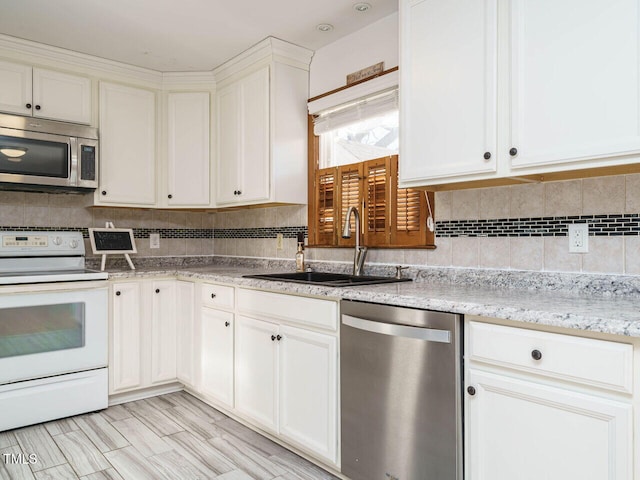 kitchen with tasteful backsplash, sink, light stone countertops, appliances with stainless steel finishes, and white cabinets