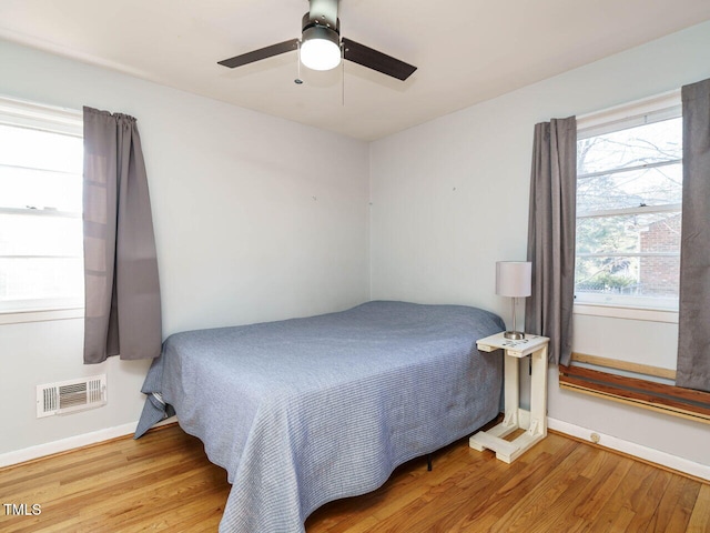 bedroom featuring ceiling fan, multiple windows, and light wood-type flooring