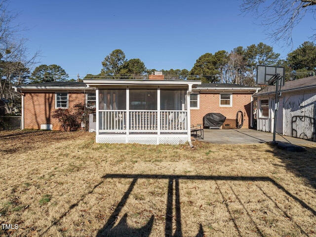 rear view of house with a lawn, a patio area, and a sunroom