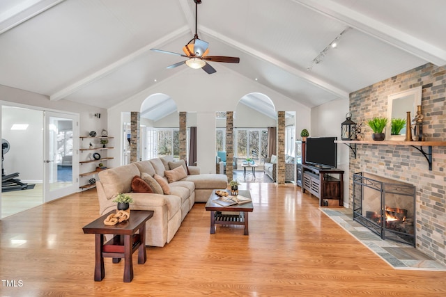 living area with vaulted ceiling with beams, a fireplace, light wood-style floors, a ceiling fan, and ornate columns