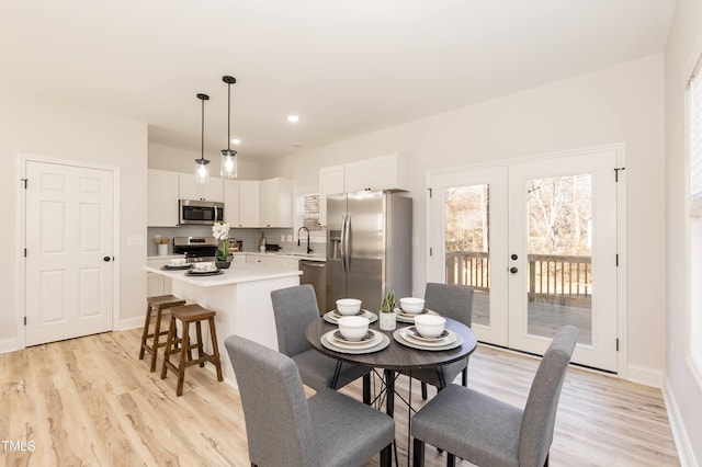 dining area with light hardwood / wood-style flooring, french doors, and sink