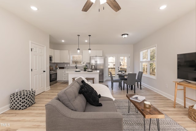 living room with light hardwood / wood-style floors, sink, and ceiling fan