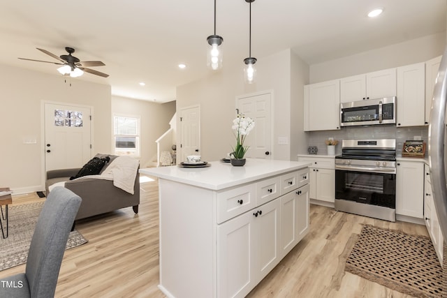 kitchen with white cabinetry, light hardwood / wood-style floors, stainless steel appliances, decorative light fixtures, and a center island