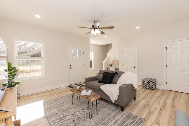 living room with ceiling fan, light wood-type flooring, and plenty of natural light