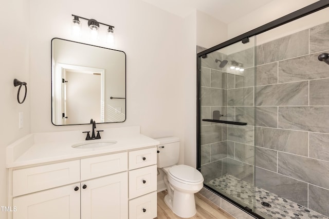 bathroom with hardwood / wood-style flooring, toilet, a shower with door, and vanity